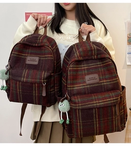 Détail d'un sac à dos vintage à carreaux avec peluche et logo de marque en cuir brun