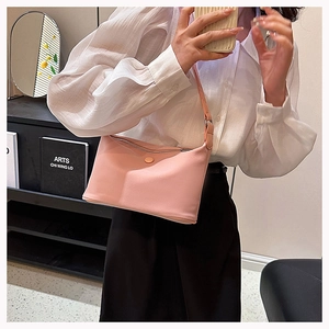 Detail of pink minimalist underarm bag with silver zipper and fine strap on a model