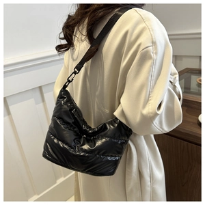 Detail of black quilted puffer shoulder bag with high-gloss nylon and adjustable strap