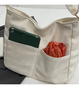 Detailed view of cream white shoulder bag featuring large front pockets for tablet and umbrella