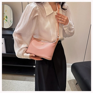 Chic pink crossbody bag with metal buckle detail shown on a stylish model's shoulder