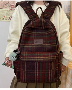 Sac à dos à carreaux classique avec breloque peluche verte porté dans un style rétro