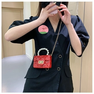 Détail d'un mini sac jelly rouge avec poignée en perles et chaîne dorée sur mannequin