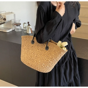 Détail du sac fourre-tout en paille tissée avec anses en cuir noir et surpiqûres blanches