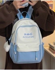 Detail view of white and blue polyester backpack with plush pendant and logo lettering