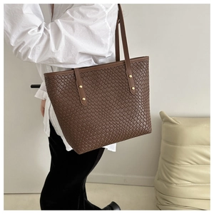 Détail d'un sac cabas marron tissé avec rivets dorés et cuir synthétique texturé durable