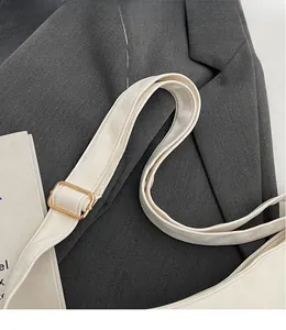 Detail of adjustable beige faux leather shoulder strap with golden metal buckle