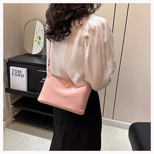 Detail view of a soft pink crossbody bag worn by a model in a modern interior setting
