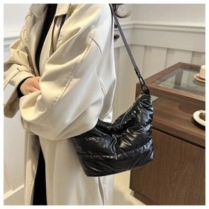 Detailed view of black quilted puffy cloud bag with glossy fabric and shoulder strap