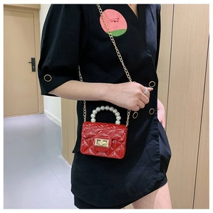 Mini sac bandoulière rouge matelassé avec poignée perle et chaîne dorée sur un enfant