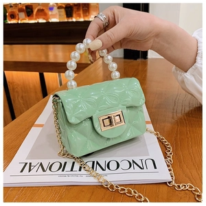 Détail du sac jelly vert menthe avec anse en perles et fine bandoulière en chaîne dorée