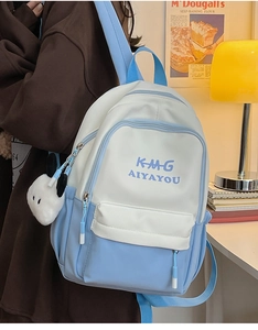 Detail of blue and white polyester backpack with plush dog charm and multi-pocket design