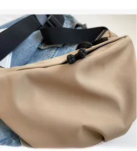 Detail shot of the beige crossbody bag featuring soft matte fabric and black braided rope tie