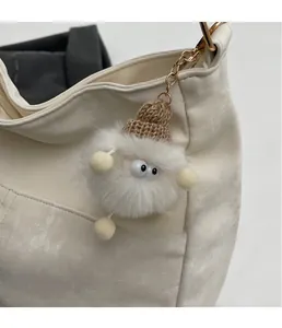 Close-up of white plush monster bag charm with brown knit hat on lychee leather handbag