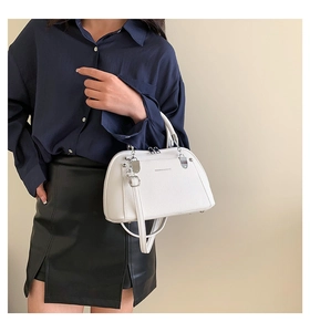 Gros plan détaillé du sac bandoulière blanc en cuir grainé avec finitions métalliques argentées