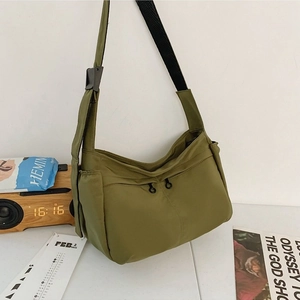 Olive green nylon crossbody bag with wide black strap and round zipper pullers