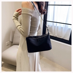 Chic black nylon shoulder bag with silver zipper and slim strap on female model