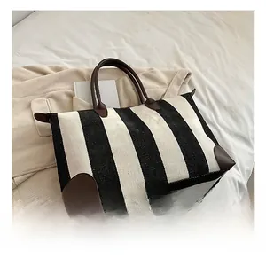 Dettaglio della borsa tote in tela a righe verticali con rifiniture in pelle marrone