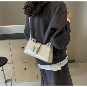 Dettaglio borsa a tracolla in pelle PU bianco crema con fiocco argento e catena in metallo
