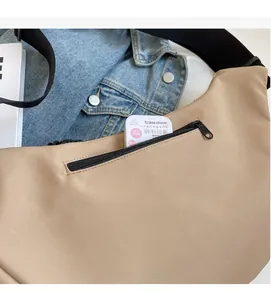 Detail of khaki nylon shoulder bag featuring a functional front zipper pocket for small items