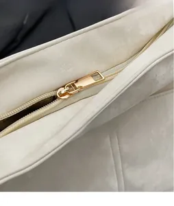 Close-up of white PU shoulder bag featuring smooth gold metal zipper and textured fabric