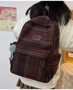 Gros plan sur la texture à carreaux rétro du sac à dos avec patch cuir et pompon en fourrure
