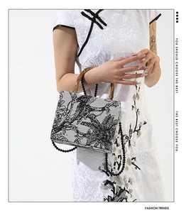 Close-up of bamboo handle and ink-wash print on a stylish rectangular handbag
