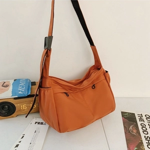 Fashionable orange nylon crossbody bag with adjustable strap in a stylish daily setting