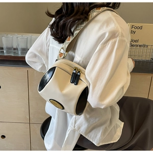 Moderne cremeweiße Zylindertasche mit gemustertem Webriemen an einem Modell getragen