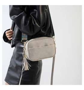 Detail of beige PU leather crossbody bag with V-shaped stitching and ethnic woven strap