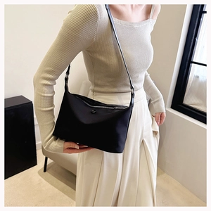 Close-up of minimalist black nylon crescent bag with smooth zipper and button details