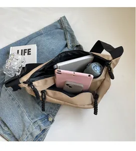 Top view of spacious khaki canvas crossbody bag filled with books, tablet, and umbrella