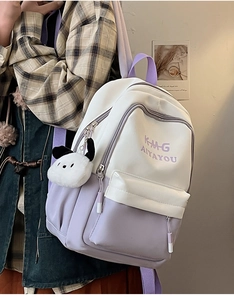 Detail of white and purple backpack with embroidery and plush dog charm accessory