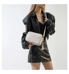 Detail view of the beige PU crossbody bag featuring V-shaped quilting and tassel detail