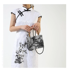 Detail of white jacquard bag with black nature totem and authentic bamboo handle