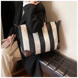 Grande borsa tote a righe alla moda con manici in pelle marrone indossata da una modella