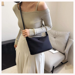 Fashionable black nylon shoulder bag styled with an elegant beige and white outfit