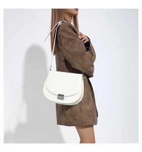 Détail du sac de selle blanc en similicuir avec boucle argentée porté par un mannequin