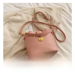 Détail du sac seau rose en cuir grainé avec finitions métalliques dorées et bandoulière