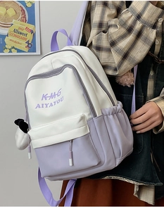 Detail view of stylish white and purple bicolor college-style backpack with doll charm