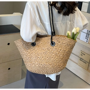 Détail du sac cabas en paille tissée avec de fines anses en cuir noir et œillets en métal