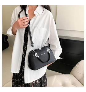 Détail d'un sac à main noir en cuir grainé avec finitions argentées sur un mannequin
