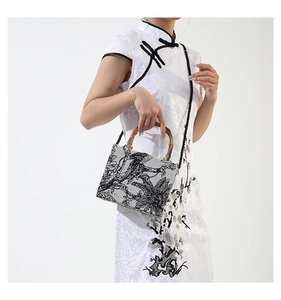 Close-up of fabric handbag with ink wash pattern, bamboo handle and woven strap on model