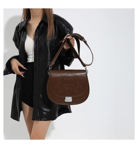 Détail du sac besace marron foncé avec motifs étoilés gaufrés et boucle métallique