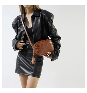 Close-up of brown PU leather crossbody bag with V-quilted pattern and stylish tassel detail