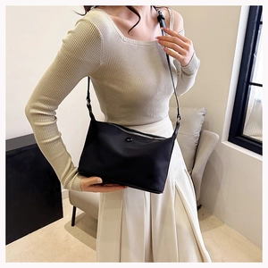 Detail of the black nylon crossbody bag featuring silver zipper and slim shoulder strap