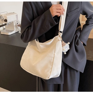 Detailed close-up of white suede crossbody bag featuring a soft plush toy pendant accessory