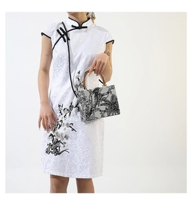Detail of rectangular handbag with bamboo handle and black and white floral landscape print