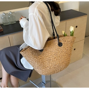 Détail du sac à main en paille tressée à la main avec de larges bandoulières noires