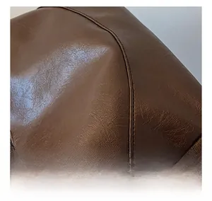Macro shot of fine stitching details and textured brown leather on the stylish dumpling bag